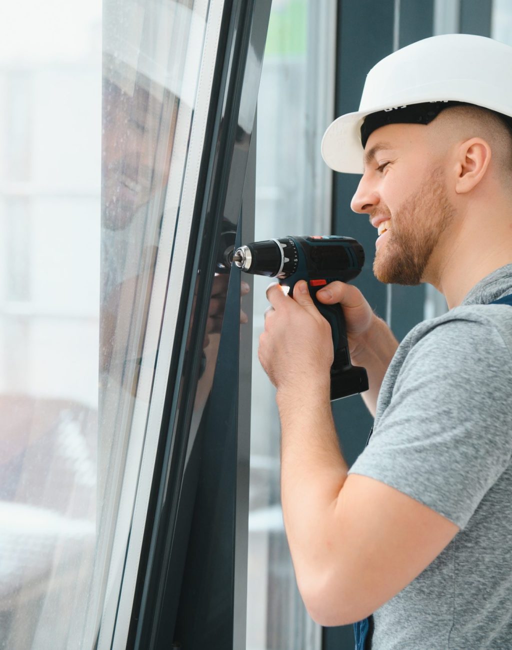Construction worker using drill while installing window indoors
